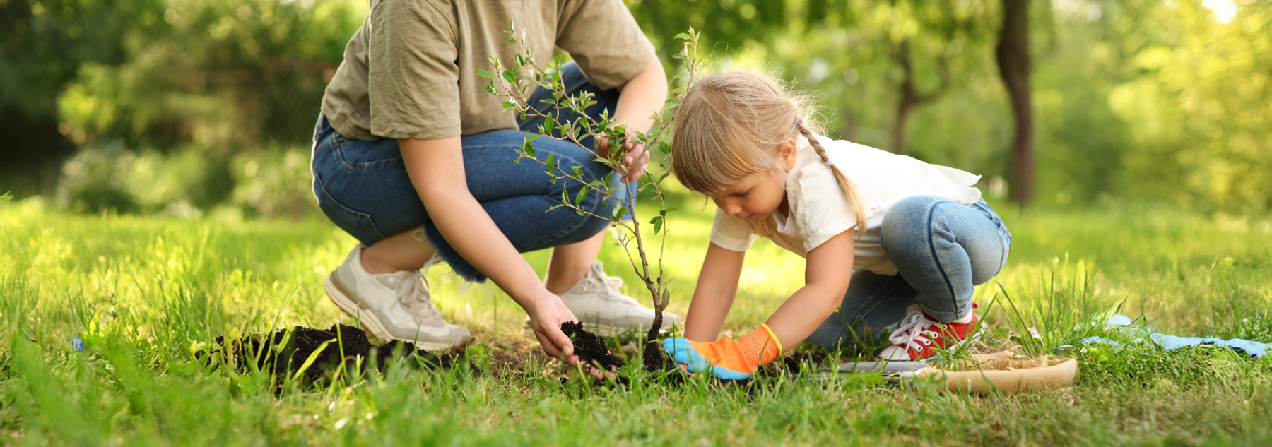 A mom and daughter plant a small tree sapling.