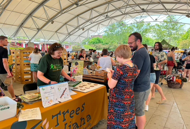 Trees Indiana connects with a parent and kid at an event in downtown Fort Wayne, Indiana.